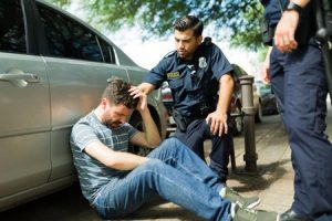 A man holds his head after a car accident while police check in on him