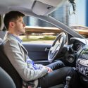 side view of a young man sitting inside autonomous car