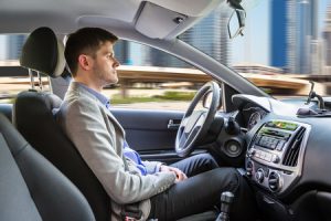 side view of a young man sitting inside autonomous car