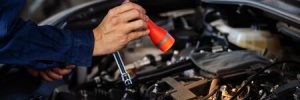 A man looks into the hood of a car with a flashlight