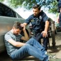 A man holds his head after a car accident while police check in on him