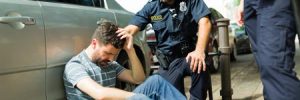 A man holds his head after a car accident while police check in on him