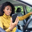 A woman looks at her phone while she's driving