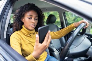 A woman looks at her phone while she's driving