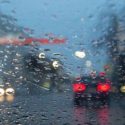 A view out of a car windshield, obscure by rain drops