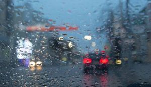 A view out of a car windshield, obscure by rain drops