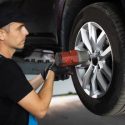 A mechanic works on a car's tire with a drill