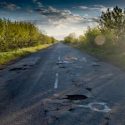 A road in poor condition with potholes and other issues