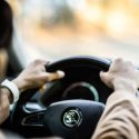 A young man holds the wheel in the correct manner while driving down an open road