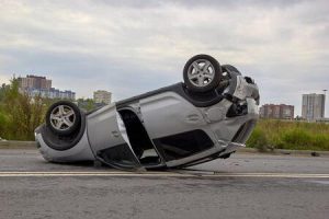 A mid-size SUV has flipped over on a city road after a vehicle collision