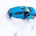 A turquoise mid-size vehicle stuck in the snow