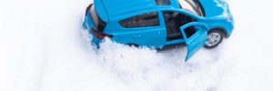 A turquoise mid-size vehicle stuck in the snow