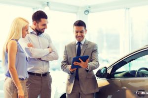 A couple listens to a car salesman show off the vehicle features