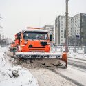 Snow plough trucks is removing removing snow and ice from city roads surfaces during snowfall. Winter, snowfall, hard traffic.