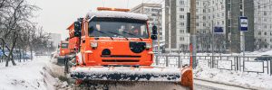 Snow plough trucks is removing removing snow and ice from city roads surfaces during snowfall. Winter, snowfall, hard traffic.