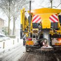 winter service truck spreading salt on the road surface to prevent icing