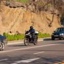 Motorcycle riding between two cars on road