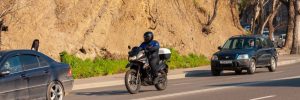 Motorcycle riding between two cars on road